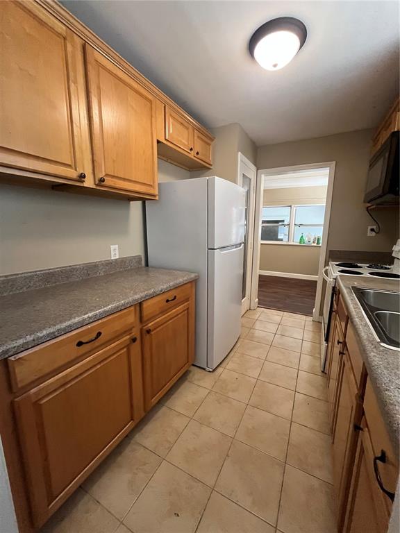 A kitchen features light wood cabinets, a white refrigerator, and tan tile flooring — 949 N GRANDVIEW STREET, MOUNT DORA, FL