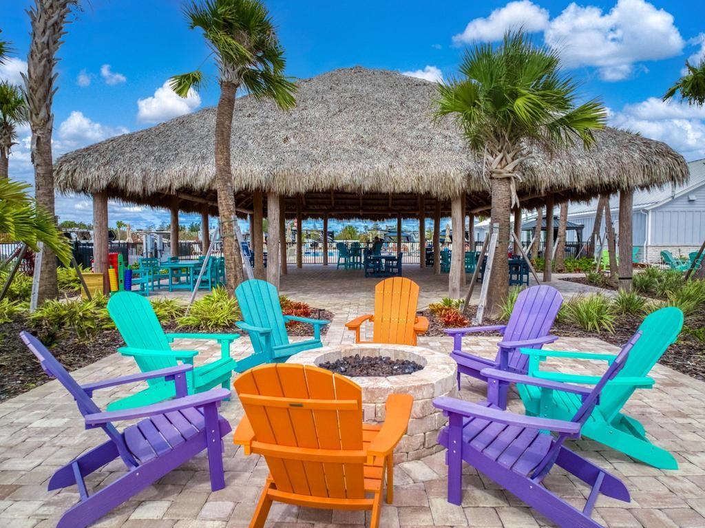 A fire pit surrounded by colorful Adirondack chairs sits on a patio beneath a tiki hut — 31 HORIZON ROAD, PUNTA GORDA, FL