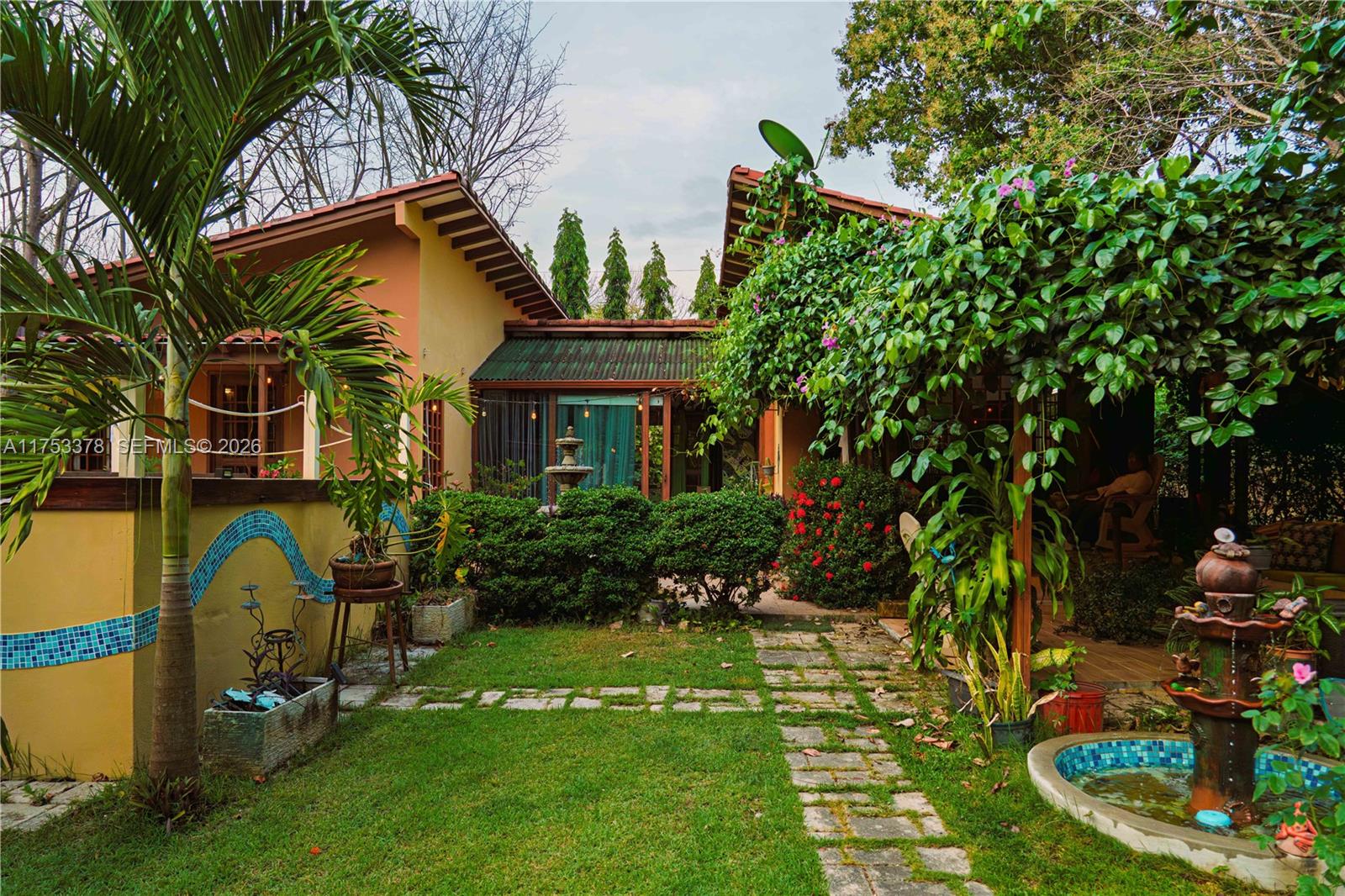 A lush backyard features a stone path, a small fountain, and a covered patio area — San Carlos Panama West Republic of Panama, al, al