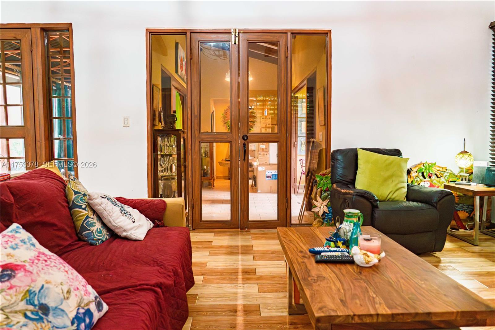A living room features a red sofa, a black armchair, and wooden French doors — San Carlos Panama West Republic of Panama, al, al