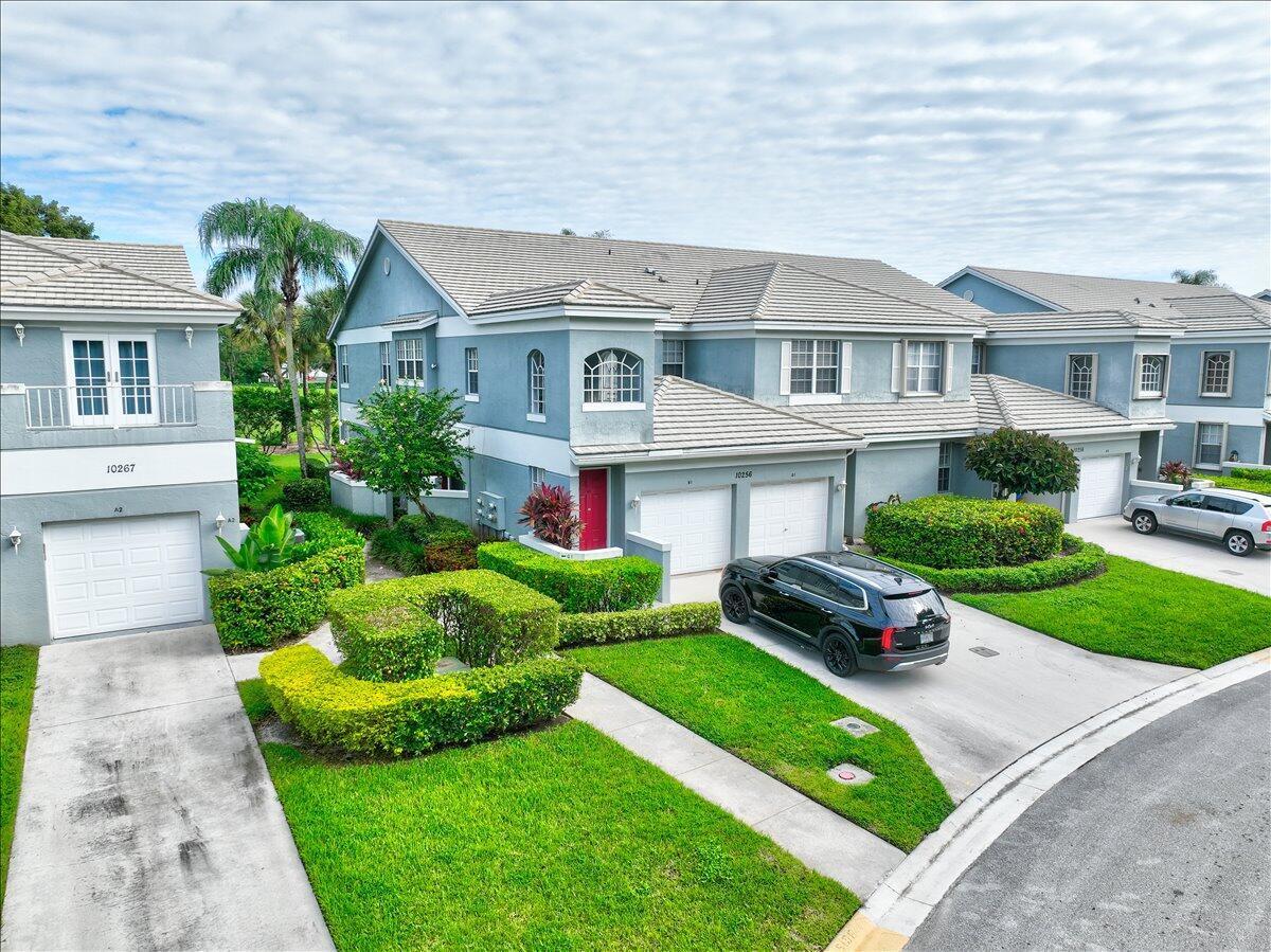 An aerial view of two-story blue townhomes with attached garages and manicured green lawns — 10256 Andover Coach Circle # G1, Lake Worth FL 33449, LAKE WORTH, FL