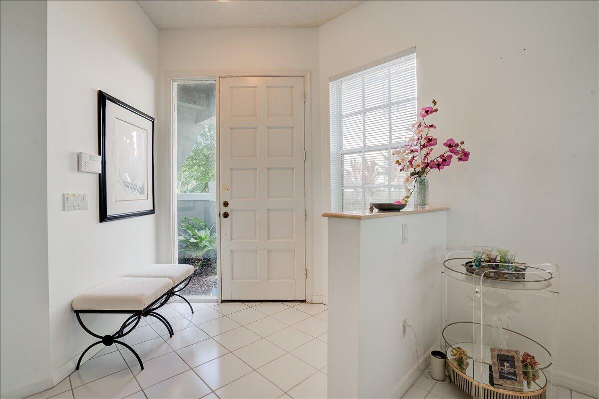 A bright entryway features white tile floors, a paneled front door, and a glass-topped console — 10256 Andover Coach Circle # G1, Lake Worth FL 33449, LAKE WORTH, FL