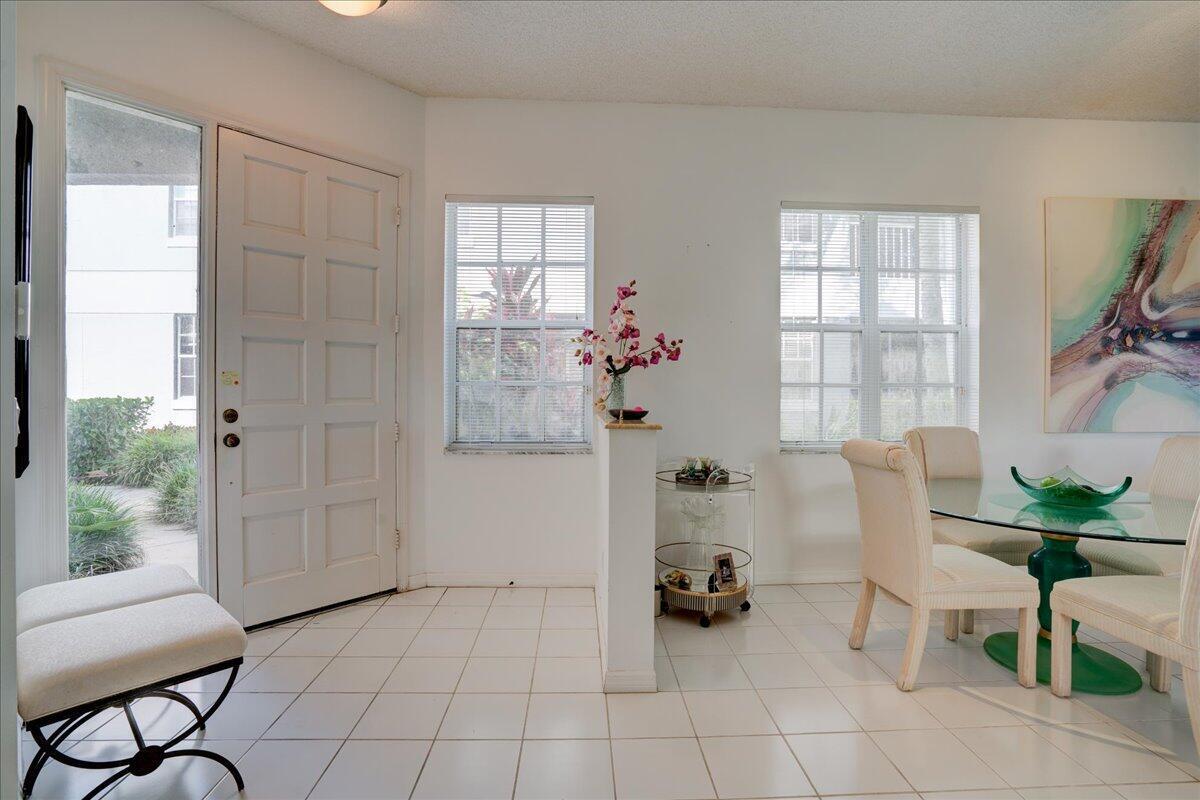 A bright entryway features white tile flooring, a glass dining table, and a front door — 10256 Andover Coach Circle # G1, Lake Worth FL 33449, LAKE WORTH, FL