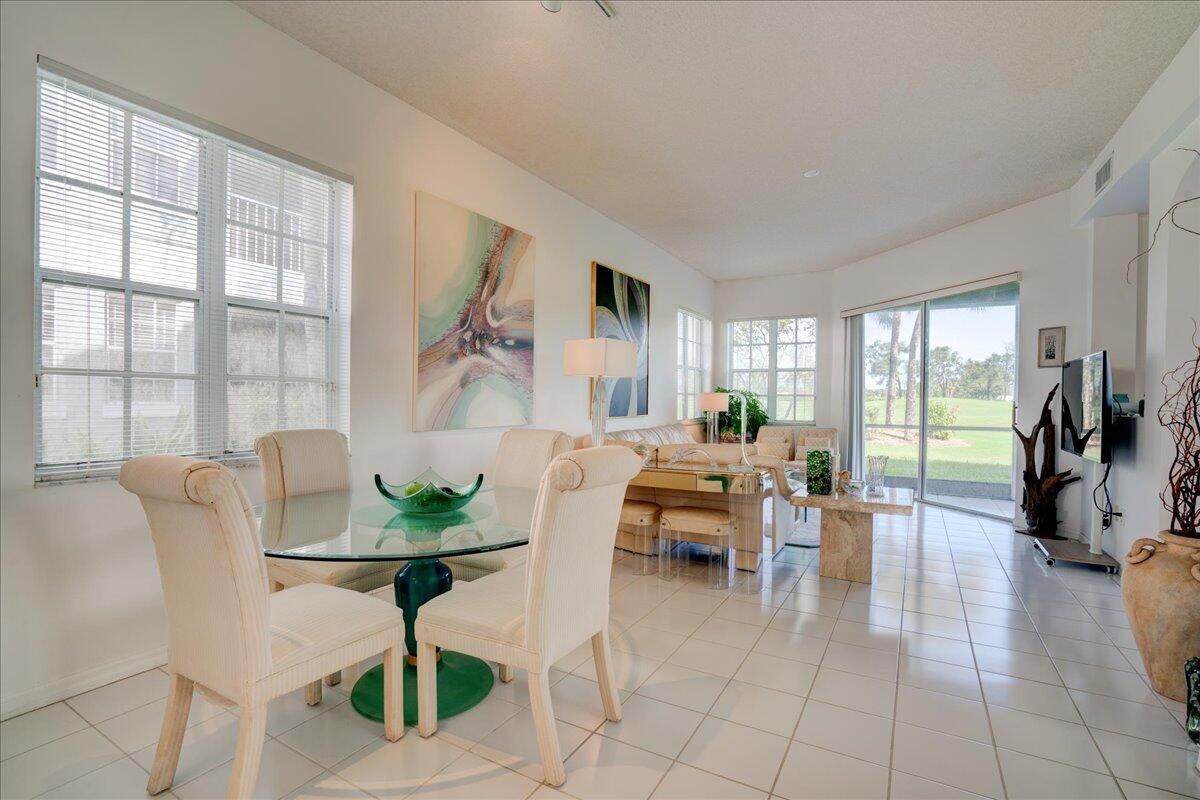 A bright dining and living area with tile floors, glass tables, and sliding glass doors — 10256 Andover Coach Circle # G1, Lake Worth FL 33449, LAKE WORTH, FL