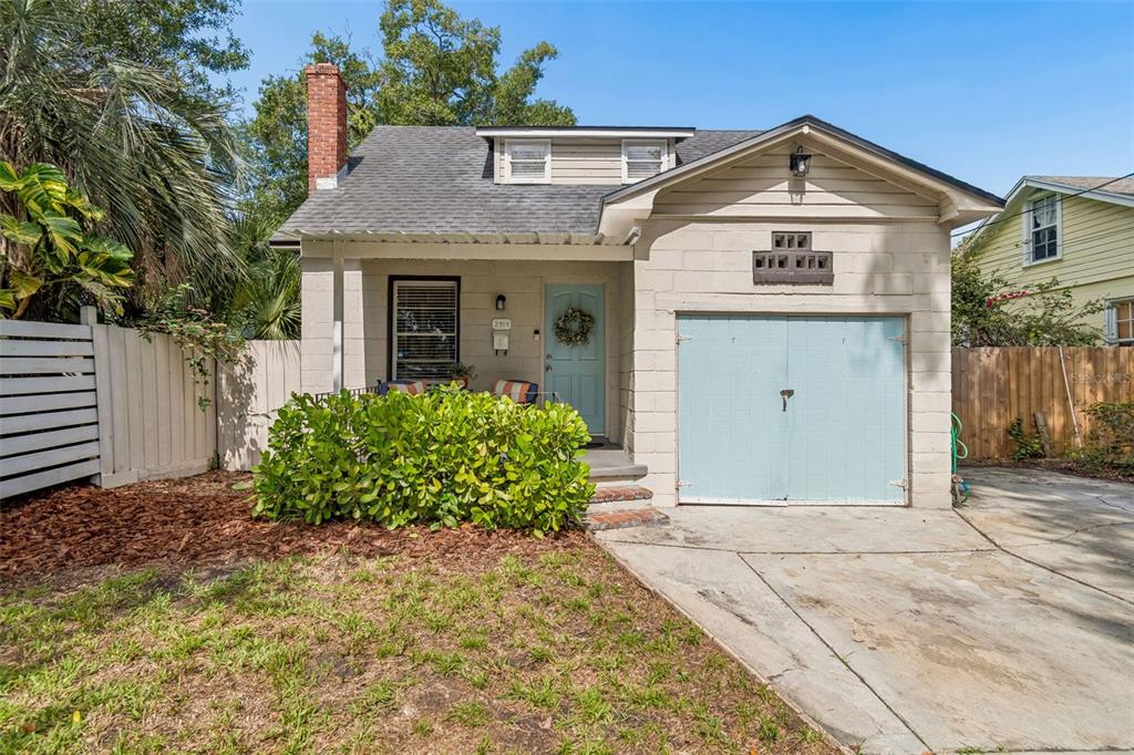 A covered front porch features two blue chairs with striped pillows and a light blue door — 2914 N WOODROW AVENUE, TAMPA, FL