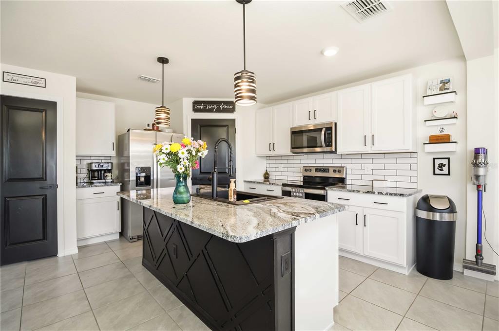 A kitchen with white cabinets, a black island, granite countertops, and stainless steel appliances — 2922 ROCK SOUND STREET, BRADENTON, FL