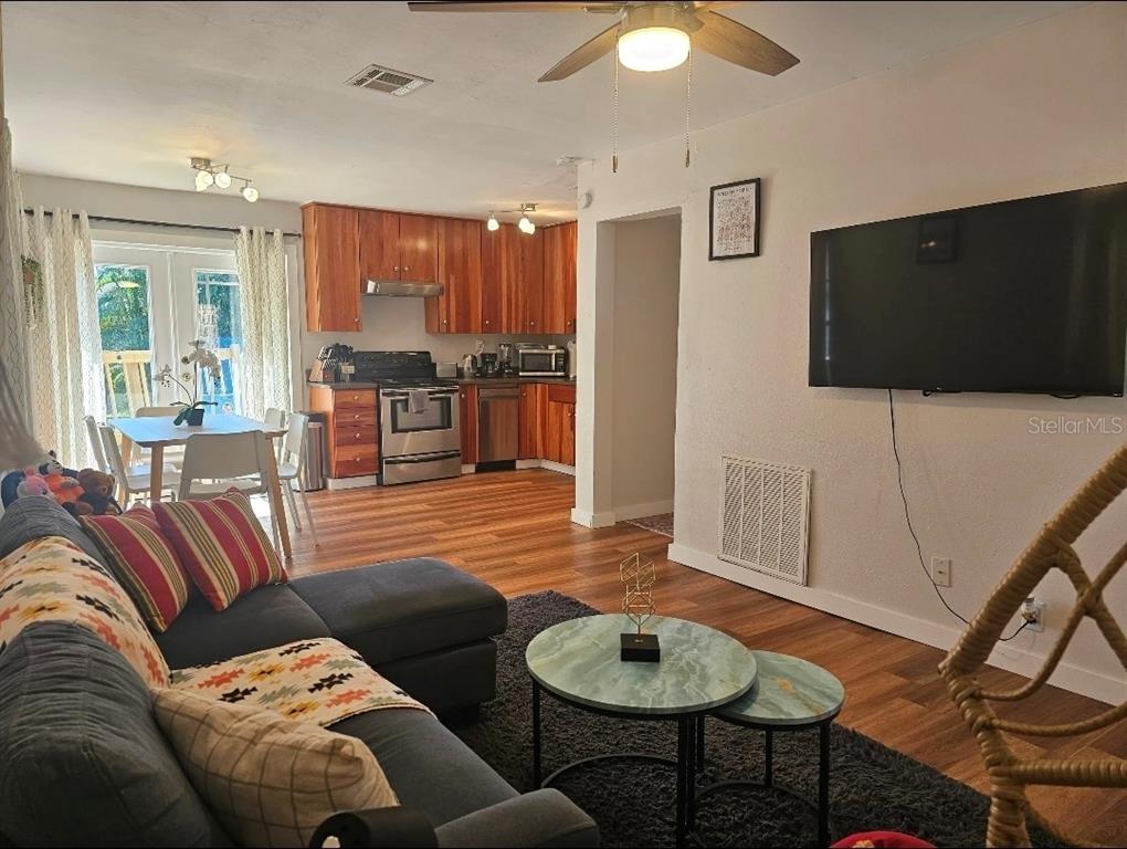 An open-concept living room and kitchen with wood flooring, stainless appliances, and a mounted television — 2015 OAKWOOD AVENUE, TAMPA, FL
