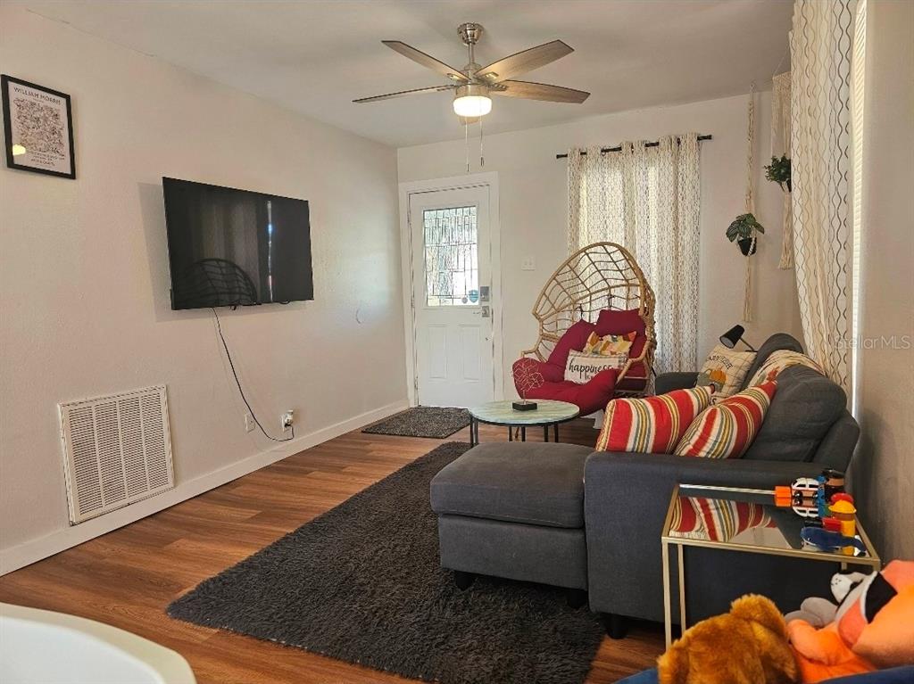 A living room features a gray sectional sofa, a hanging chair, and a wall-mounted television — 2015 OAKWOOD AVENUE, TAMPA, FL