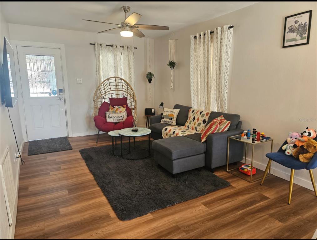A living room features wood-look flooring, a gray sectional sofa, and a hanging wicker chair — 2015 OAKWOOD AVENUE, TAMPA, FL
