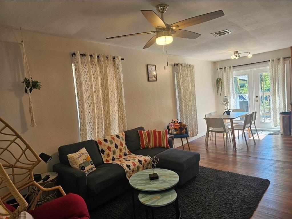 A living room with a dark sectional sofa, a ceiling fan, and an adjacent dining area — 2015 OAKWOOD AVENUE, TAMPA, FL