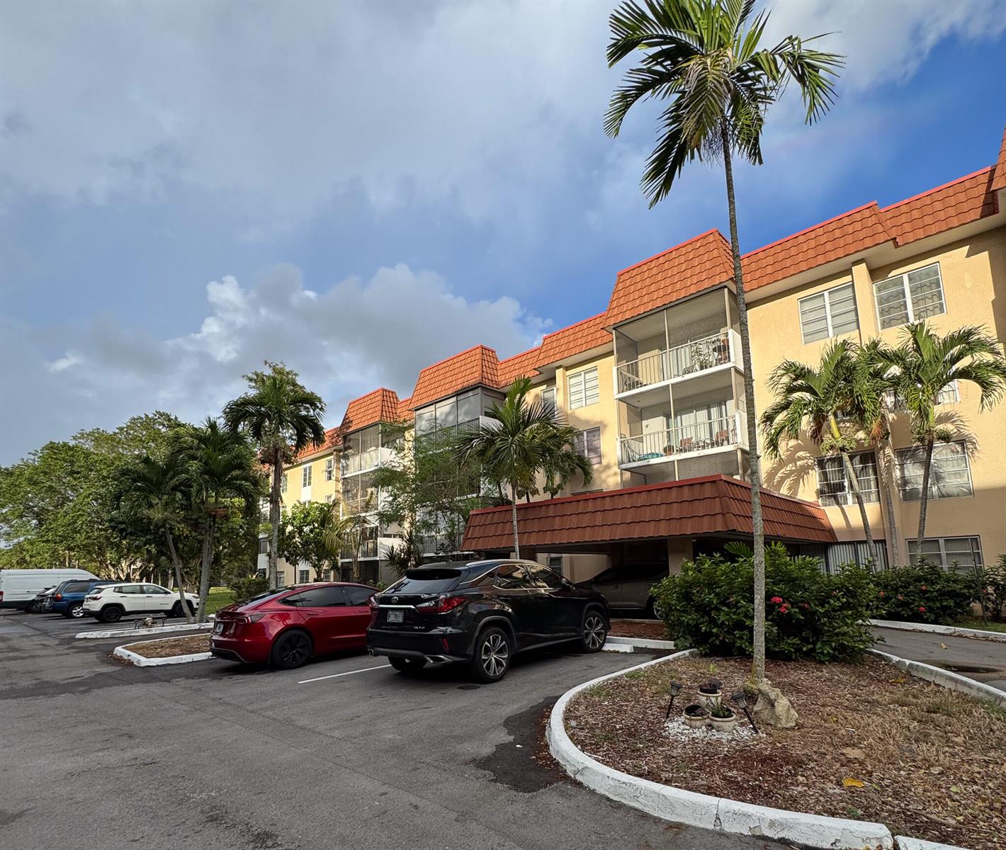 A multi-story apartment building with a red tile roof and palm trees in the parking lot — 4166 Inverrary Drive # 104, Lauderhill FL 33319, LAUDERHILL, FL