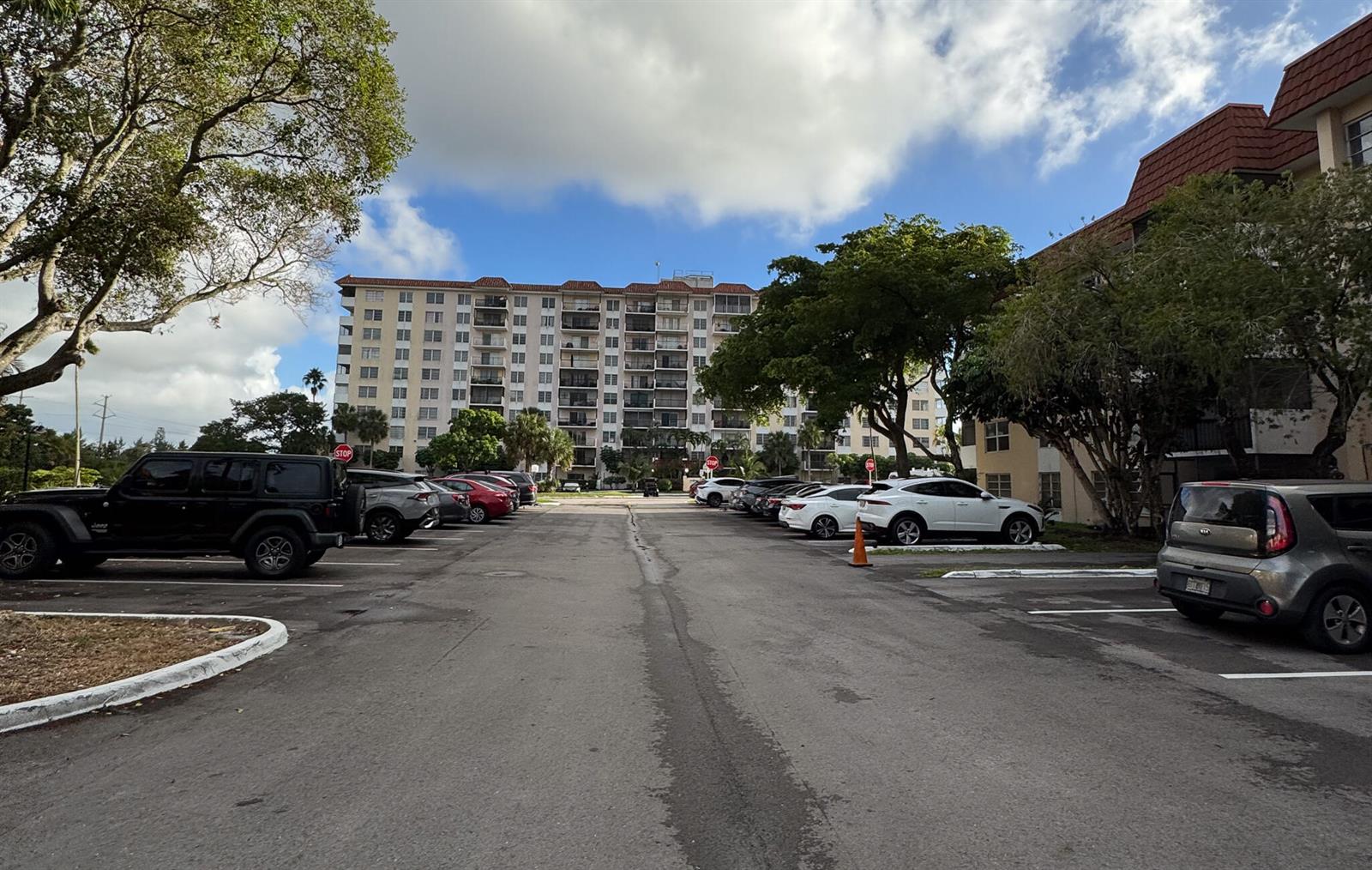A parking lot sits in front of a multi-story apartment building under a cloudy sky — 4166 Inverrary Drive # 104, Lauderhill FL 33319, LAUDERHILL, FL