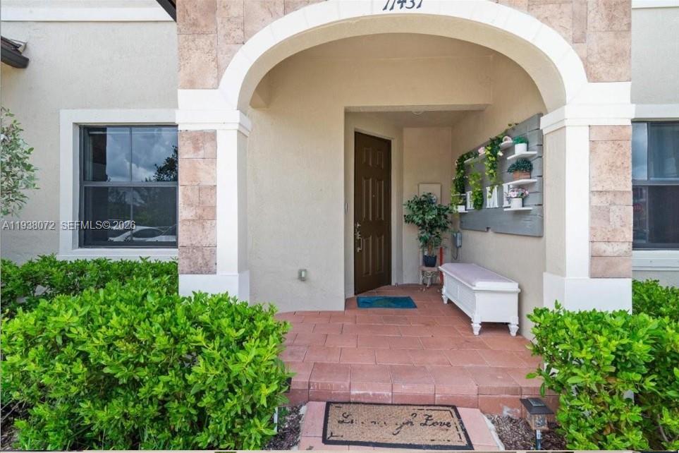 The front entrance features a covered porch with a tiled floor, bench, and wall decor — 11431 W 32nd Ln, Hialeah FL 33018, HIALEAH, FL