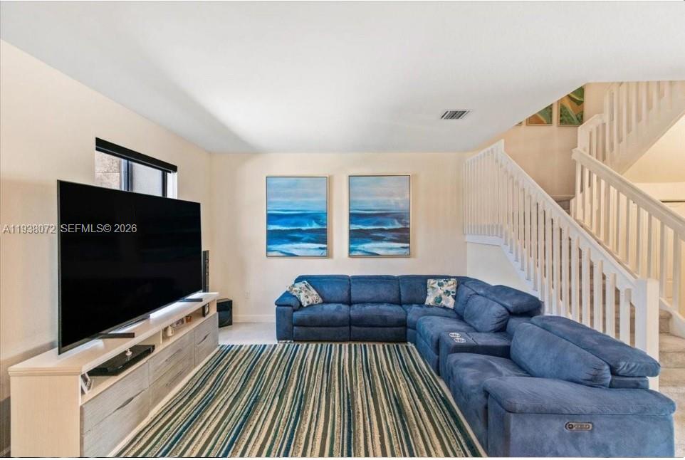 A living room features a blue sectional sofa, a large television, and a striped rug — 11431 W 32nd Ln, Hialeah FL 33018, HIALEAH, FL