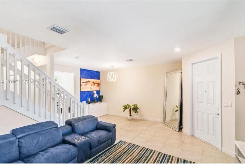 A living room features a blue sectional sofa, a staircase, and a large floor mirror — 11431 W 32nd Ln, Hialeah FL 33018, HIALEAH, FL