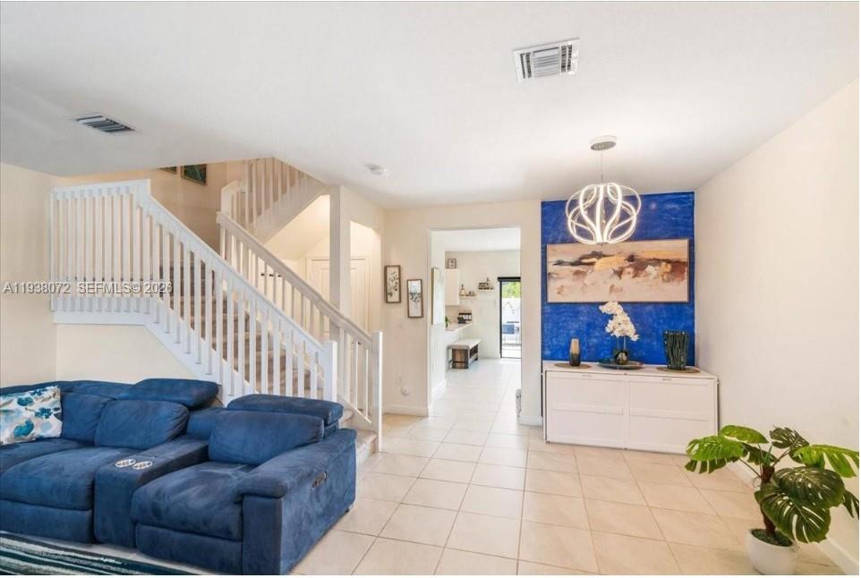 A living room features a blue sofa, a staircase, and a blue accent wall with artwork — 11431 W 32nd Ln, Hialeah FL 33018, HIALEAH, FL