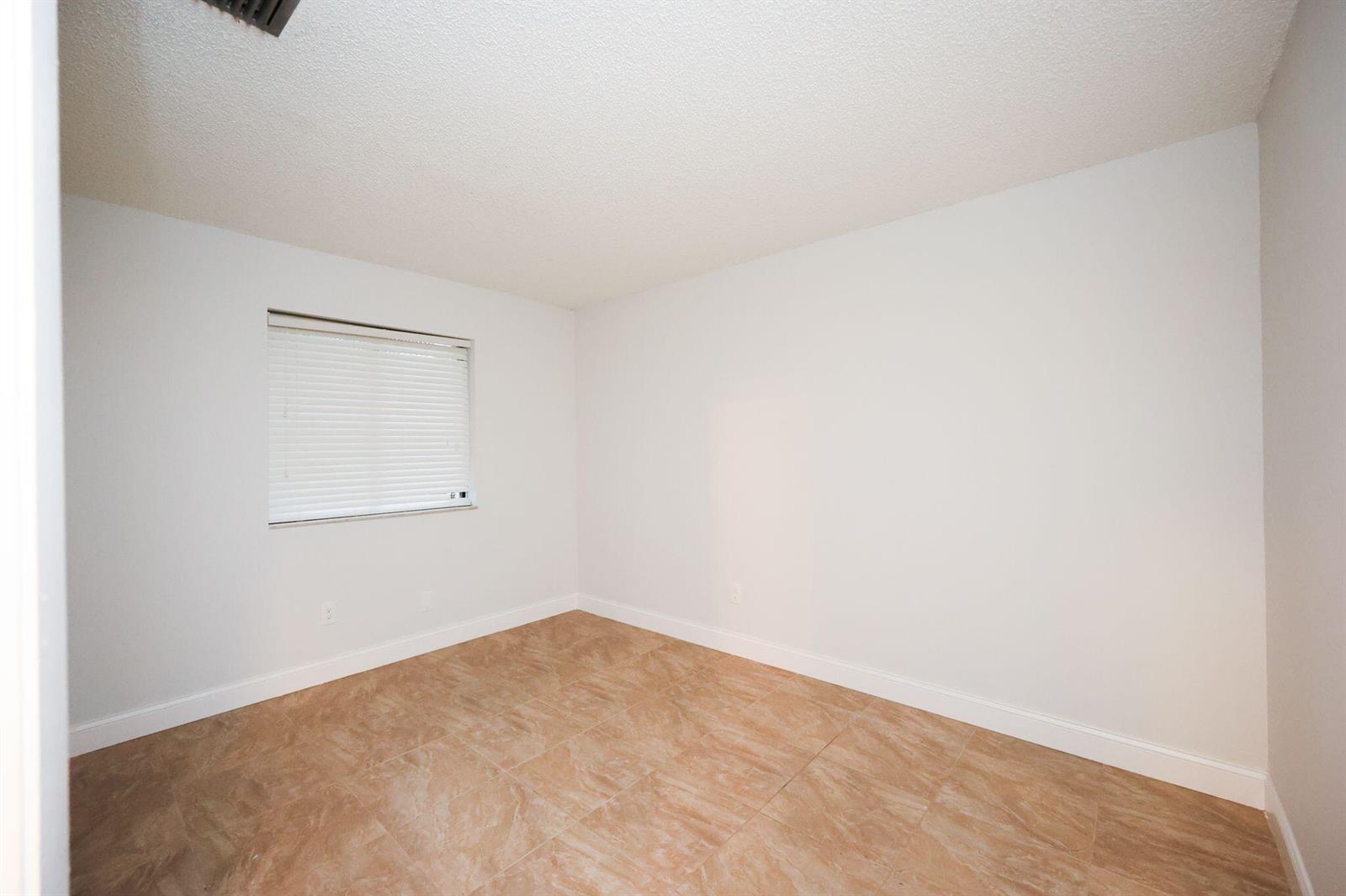 An empty bedroom features white walls, a single window with blinds, and light-colored tile flooring — 10127 E Boca Bend E # B2, Boca Raton FL 33428, BOCA RATON, FL
