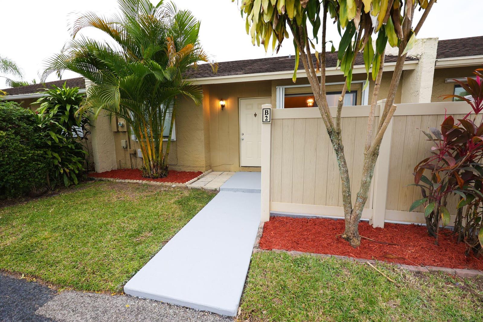 A tan exterior of a single-story unit with a gray walkway and a privacy fence — 10127 E Boca Bend E # B2, Boca Raton FL 33428, BOCA RATON, FL