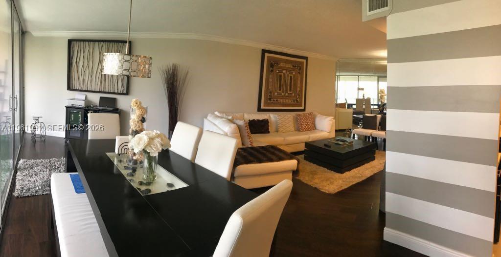 A dining area with a black table leads into a living room with white furniture — 6901 Environ Blvd # 5F, Lauderhill FL 33319, LAUDERHILL, FL