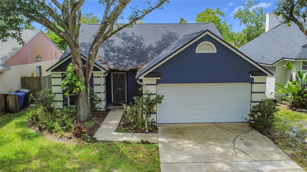 A blue single-story house with a white garage door and a concrete walkway — 1012 MALCOLM COURT, OVIEDO, FL
