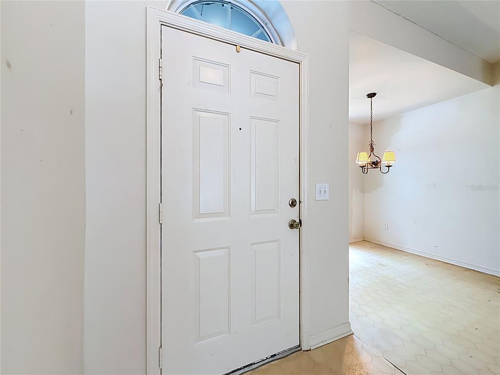 A white front door with a transom window opens into a room with a chandelier — 1012 MALCOLM COURT, OVIEDO, FL