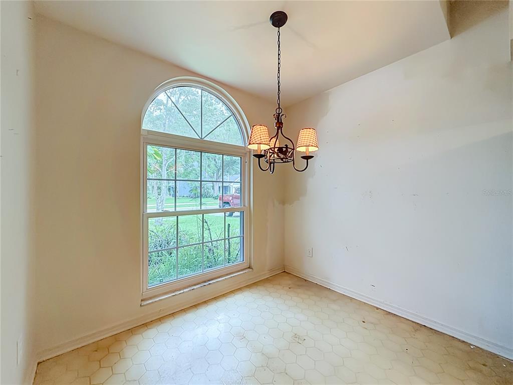 An empty dining area features a large arched window, a chandelier, and hexagonal floor tiles — 1012 MALCOLM COURT, OVIEDO, FL