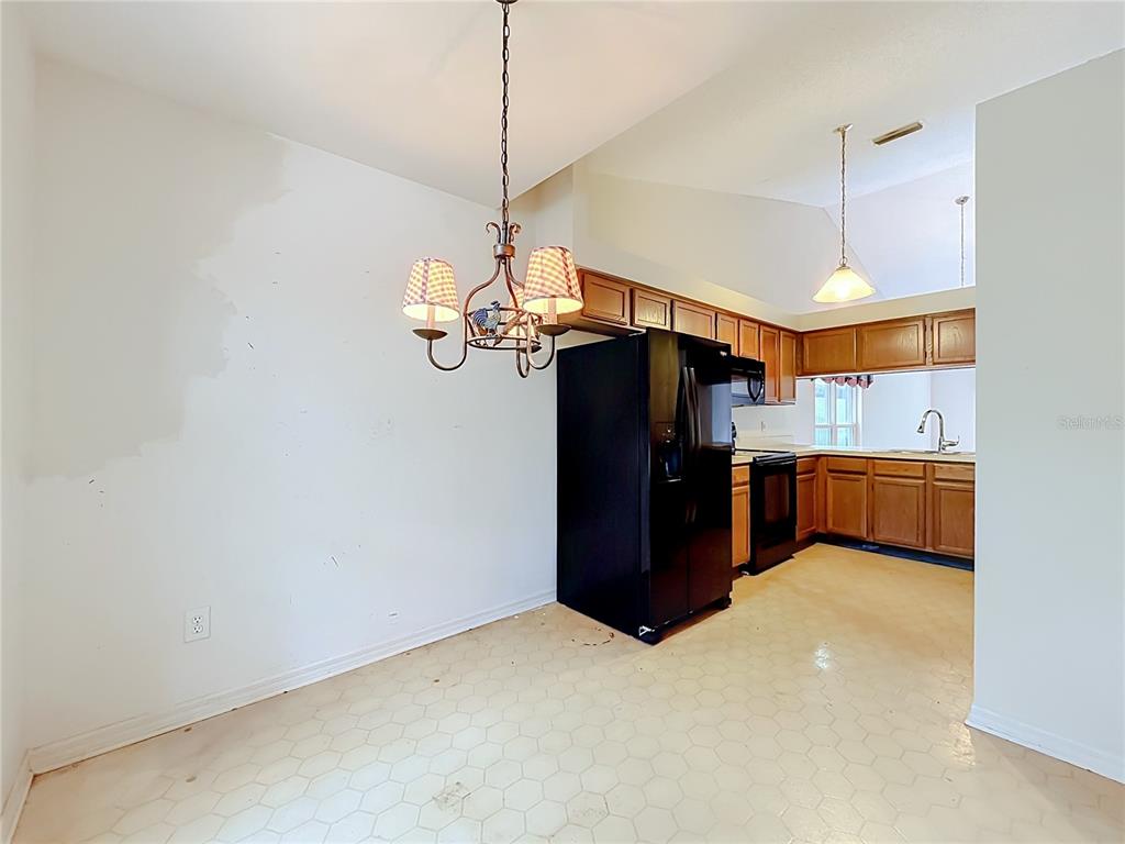 A dining area with a chandelier, hexagonal floor tiles, and an adjacent kitchen with cabinets — 1012 MALCOLM COURT, OVIEDO, FL