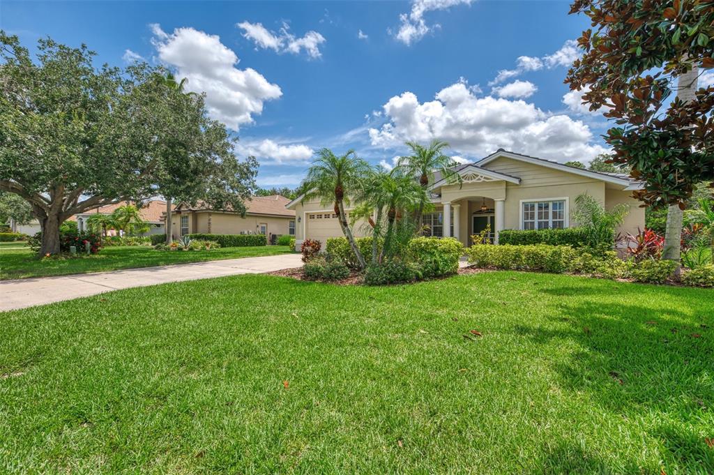 A single-story suburban house with a tan exterior, a concrete driveway, and a manicured lawn — 6644 BUTLERS CREST DRIVE, BRADENTON, FL