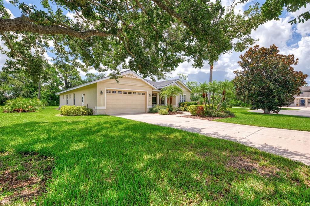 A single-story house with a beige stucco exterior, a two-car garage, and a concrete driveway — 6644 BUTLERS CREST DRIVE, BRADENTON, FL