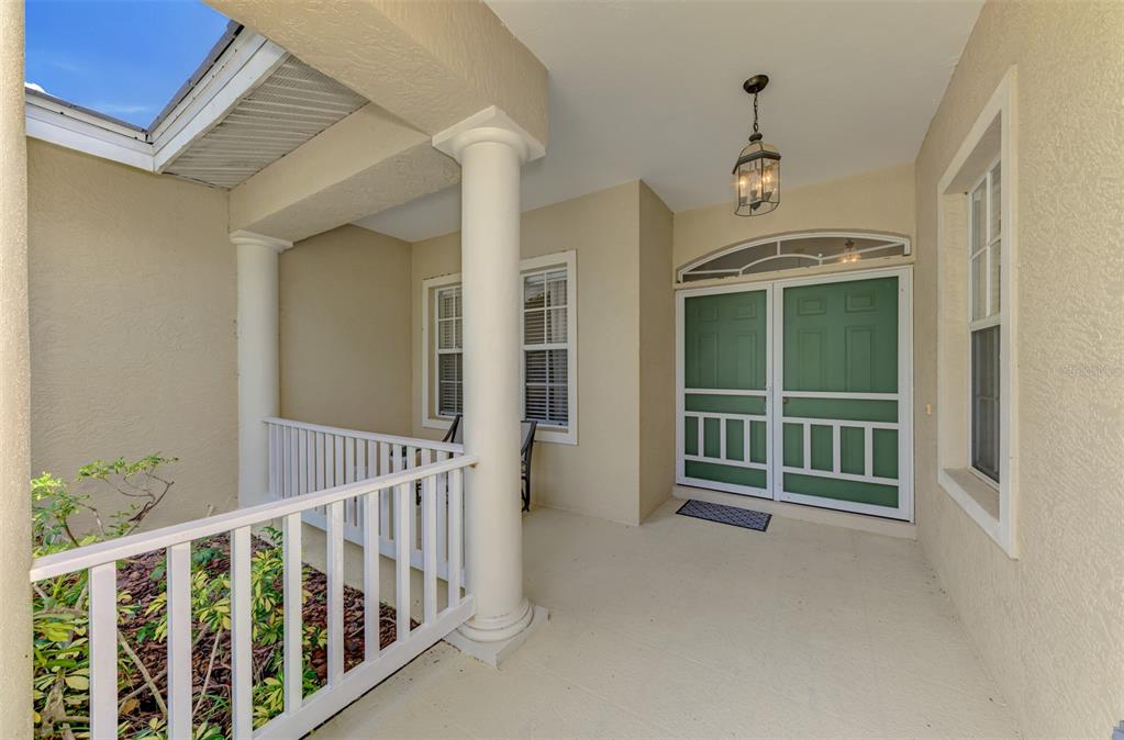 A covered front porch features white columns, a railing, and a green double screen door — 6644 BUTLERS CREST DRIVE, BRADENTON, FL