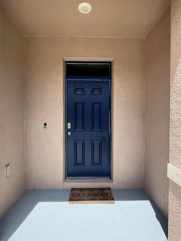 A blue front door with a transom window and a doormat sits under a porch — 1370 YELLOW FINCH DRIVE, DAVENPORT, FL