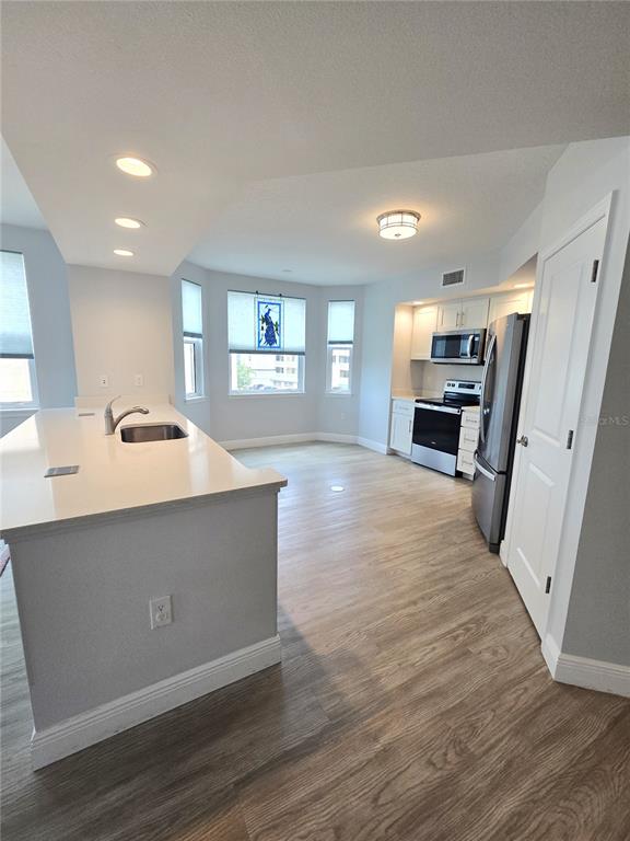 A kitchen features a white island with a sink, stainless steel appliances, and light flooring — 960 STARKEY ROAD UNIT 9206, LARGO, FL