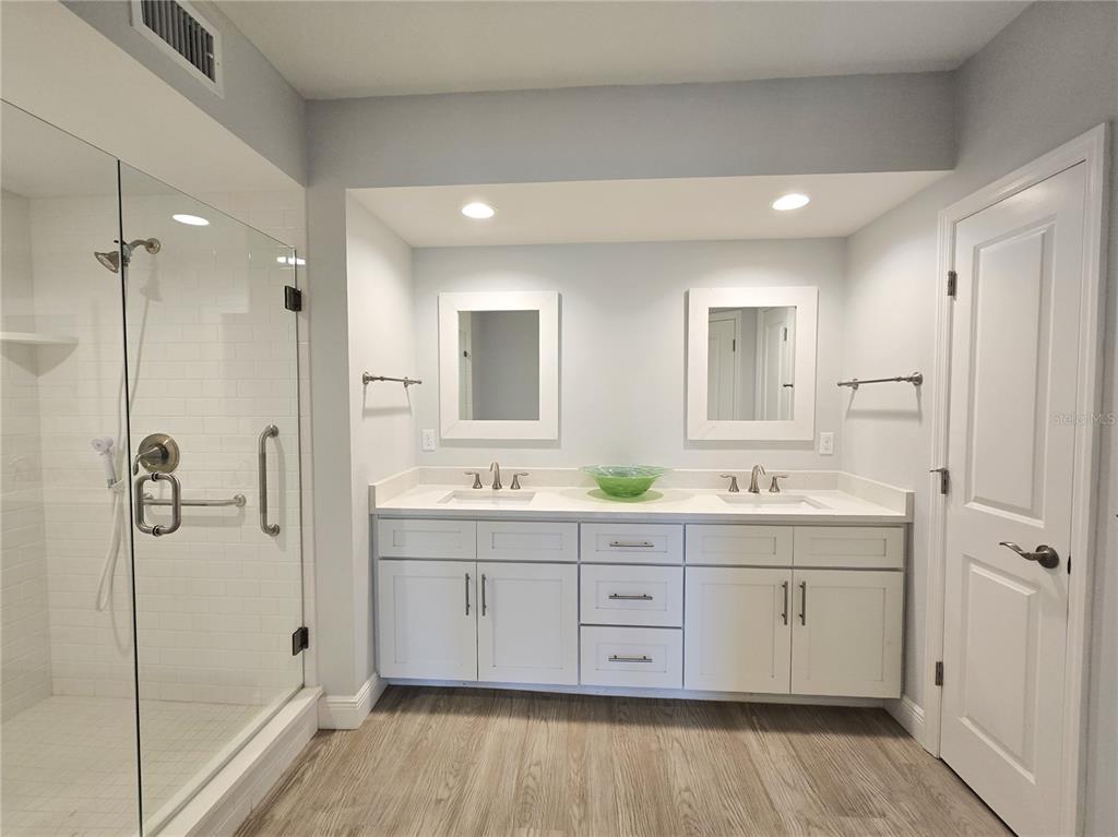 A bathroom features a double vanity with white cabinets, two mirrors, and a glass shower — 960 STARKEY ROAD UNIT 9206, LARGO, FL