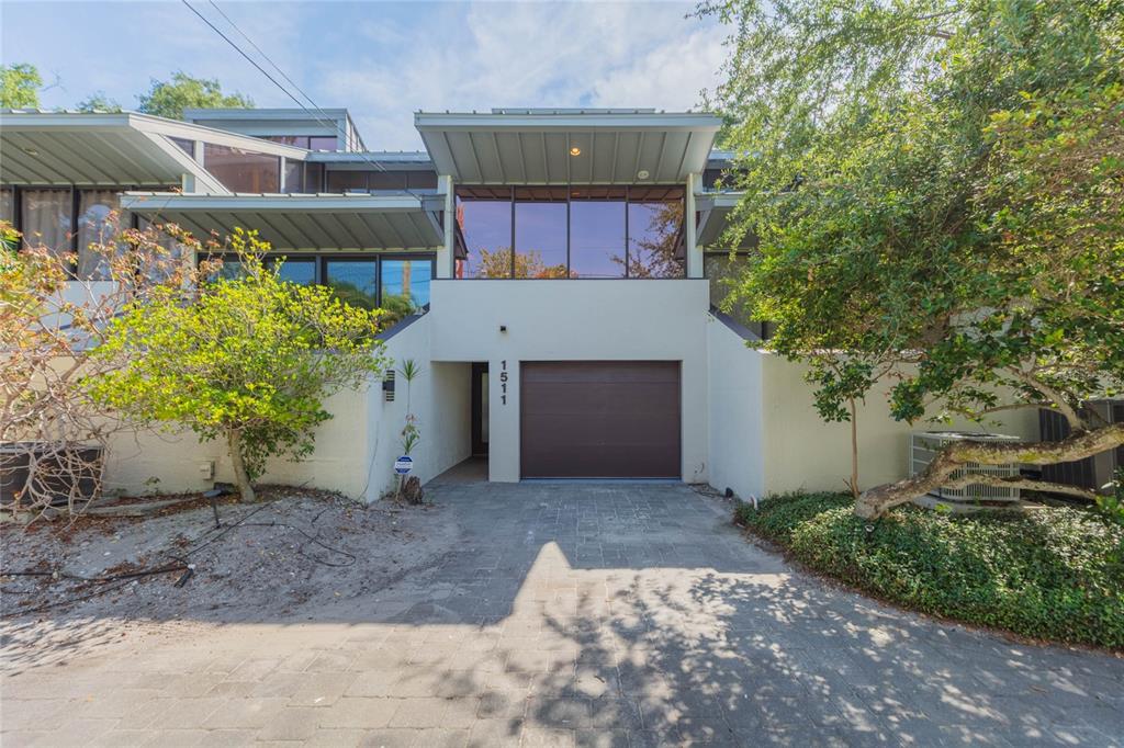 A modern two-story house with a brown garage door, flat roof, and large tinted windows — 1511 S BAY VILLA PLACE, TAMPA, FL