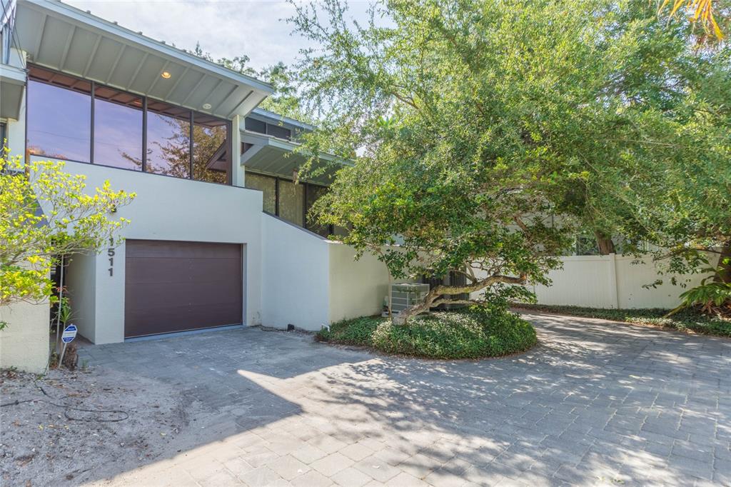 A modern house exterior features a garage, large windows, and a paved driveway with landscaping — 1511 S BAY VILLA PLACE, TAMPA, FL