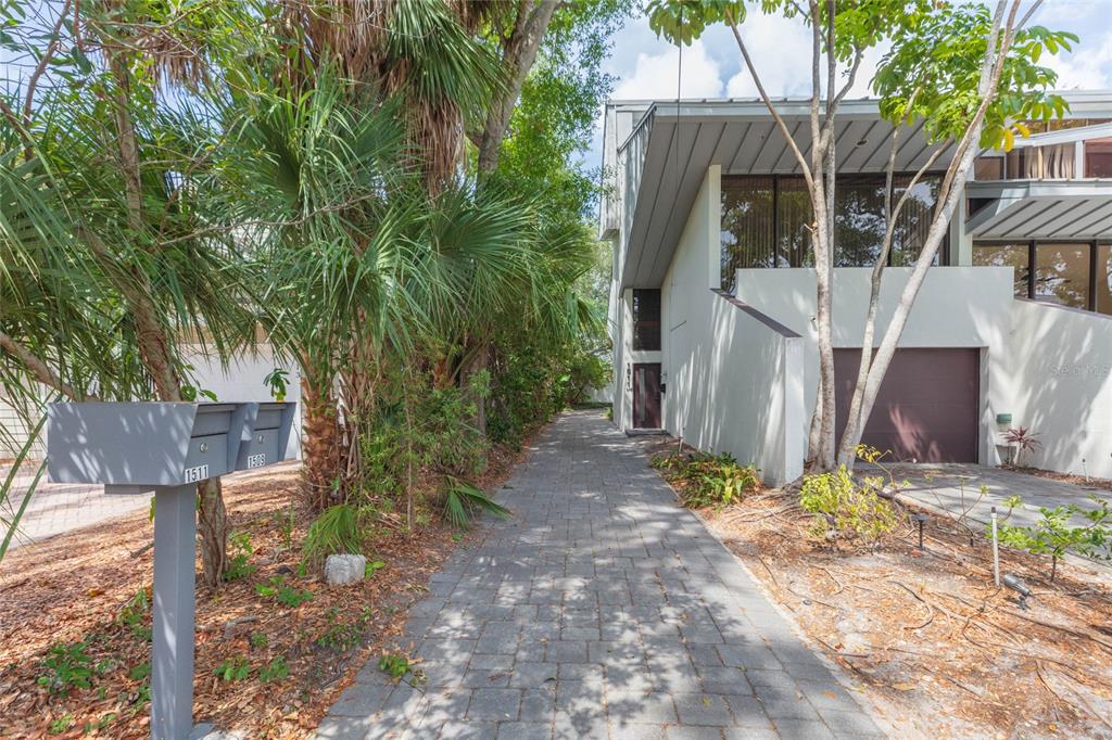 A paved walkway leads toward the entrance of a modern multi-story home with a garage — 1511 S BAY VILLA PLACE, TAMPA, FL
