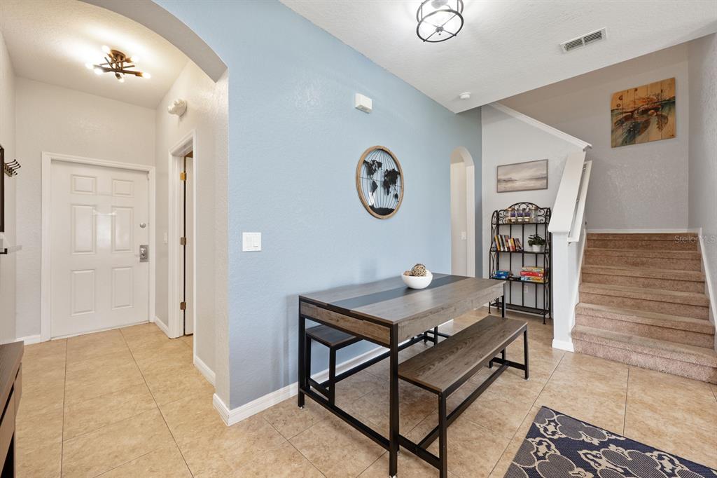 An entryway features a dining table with benches, a blue accent wall, and carpeted stairs — 2714 CALABRIA AVENUE, DAVENPORT, FL