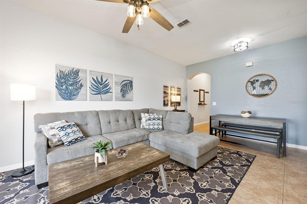 A living room features a gray sectional sofa, a wooden coffee table, and a dining table — 2714 CALABRIA AVENUE, DAVENPORT, FL
