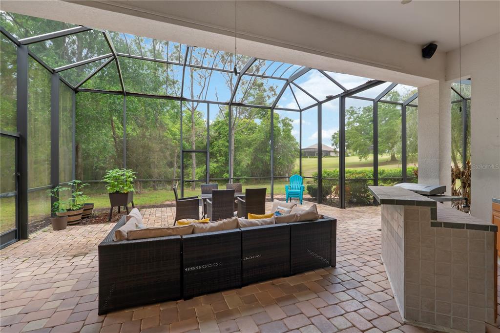 A screened-in patio features a brick paver floor, outdoor furniture, and a built-in bar — 5204 GREENS DRIVE, LADY LAKE, FL
