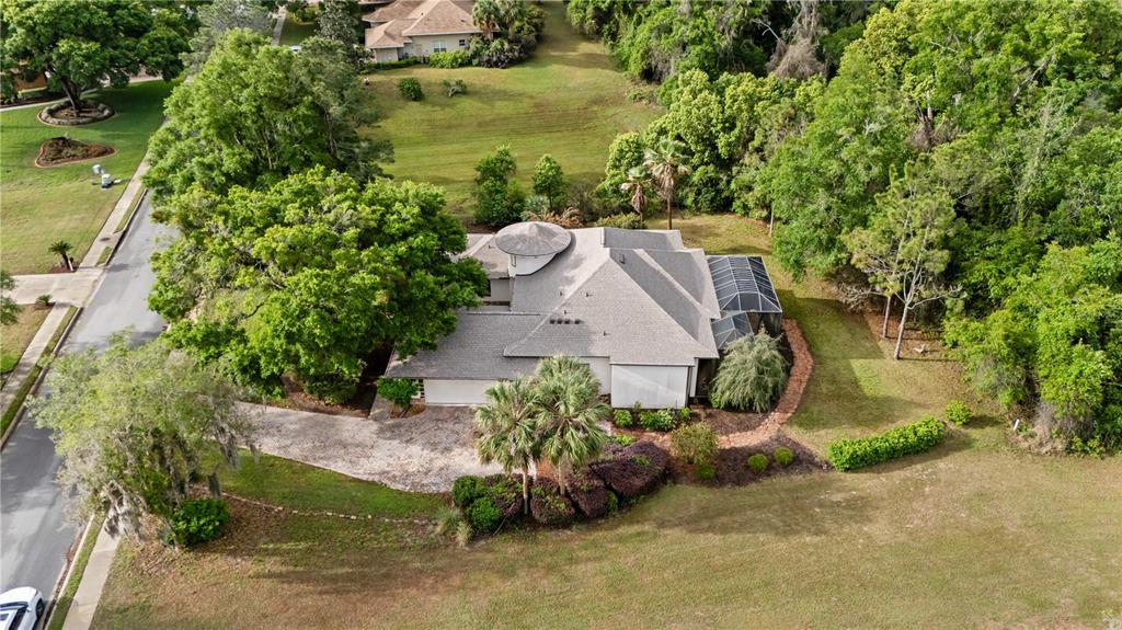 An aerial view shows a house with a circular turret, a screened lanai, and landscaping — 5204 GREENS DRIVE, LADY LAKE, FL