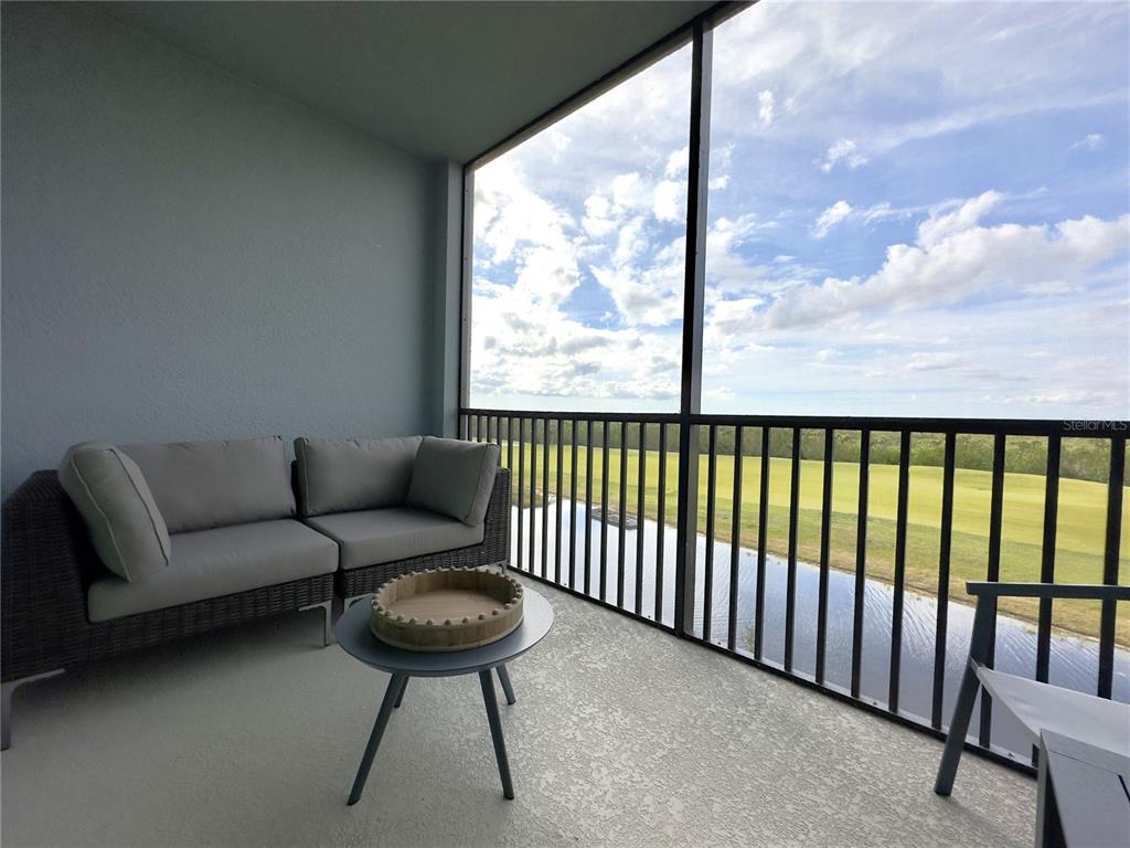 A screened-in balcony features a gray sofa, a small round table, and a golf course view — 14061 HERITAGE LANDING BOULEVARD UNIT 434, PUNTA GORDA, FL