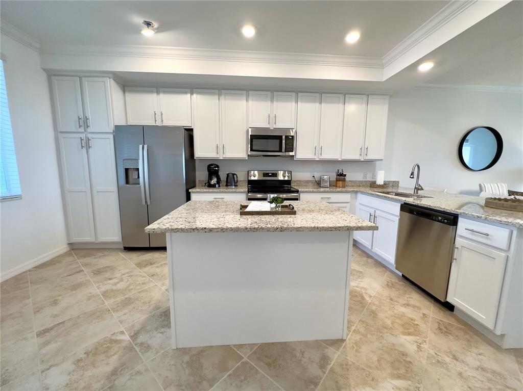 A kitchen features white cabinets, granite countertops, stainless steel appliances, and a central island — 14061 HERITAGE LANDING BOULEVARD UNIT 434, PUNTA GORDA, FL