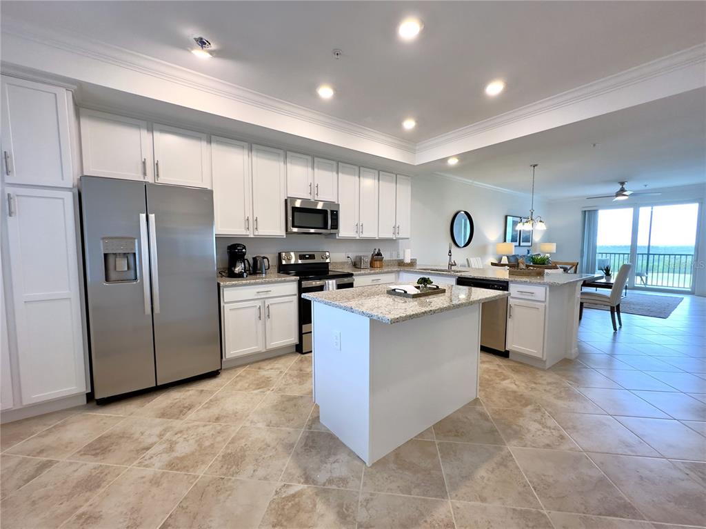 A kitchen features white cabinets, granite countertops, stainless steel appliances, and a central island — 14061 HERITAGE LANDING BOULEVARD UNIT 434, PUNTA GORDA, FL