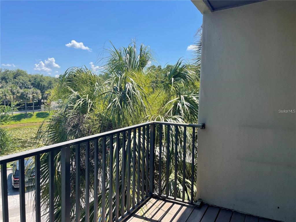 A balcony with a metal railing overlooks a pond and palm trees under a blue sky — 216 AFTON SQUARE UNIT 309, ALTAMONTE SPRINGS, FL