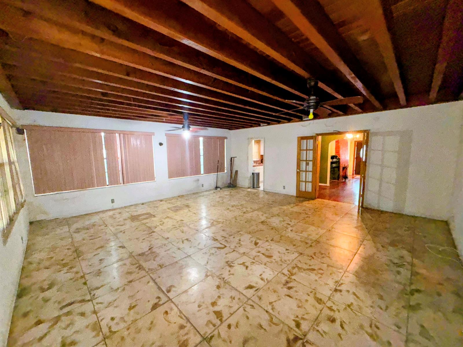 A large, empty living room features exposed wood ceiling beams and tiled flooring — 424 NE 72nd Street, Miami FL 33138, MIAMI, FL