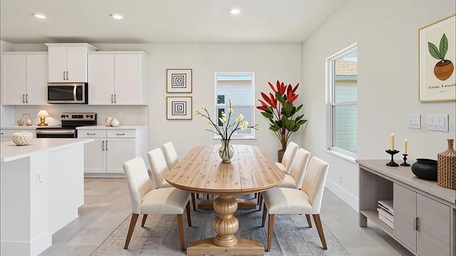 A dining area with a wooden table and white chairs sits adjacent to a white kitchen — 17035 NW 180TH TERRACE, ALACHUA, FL