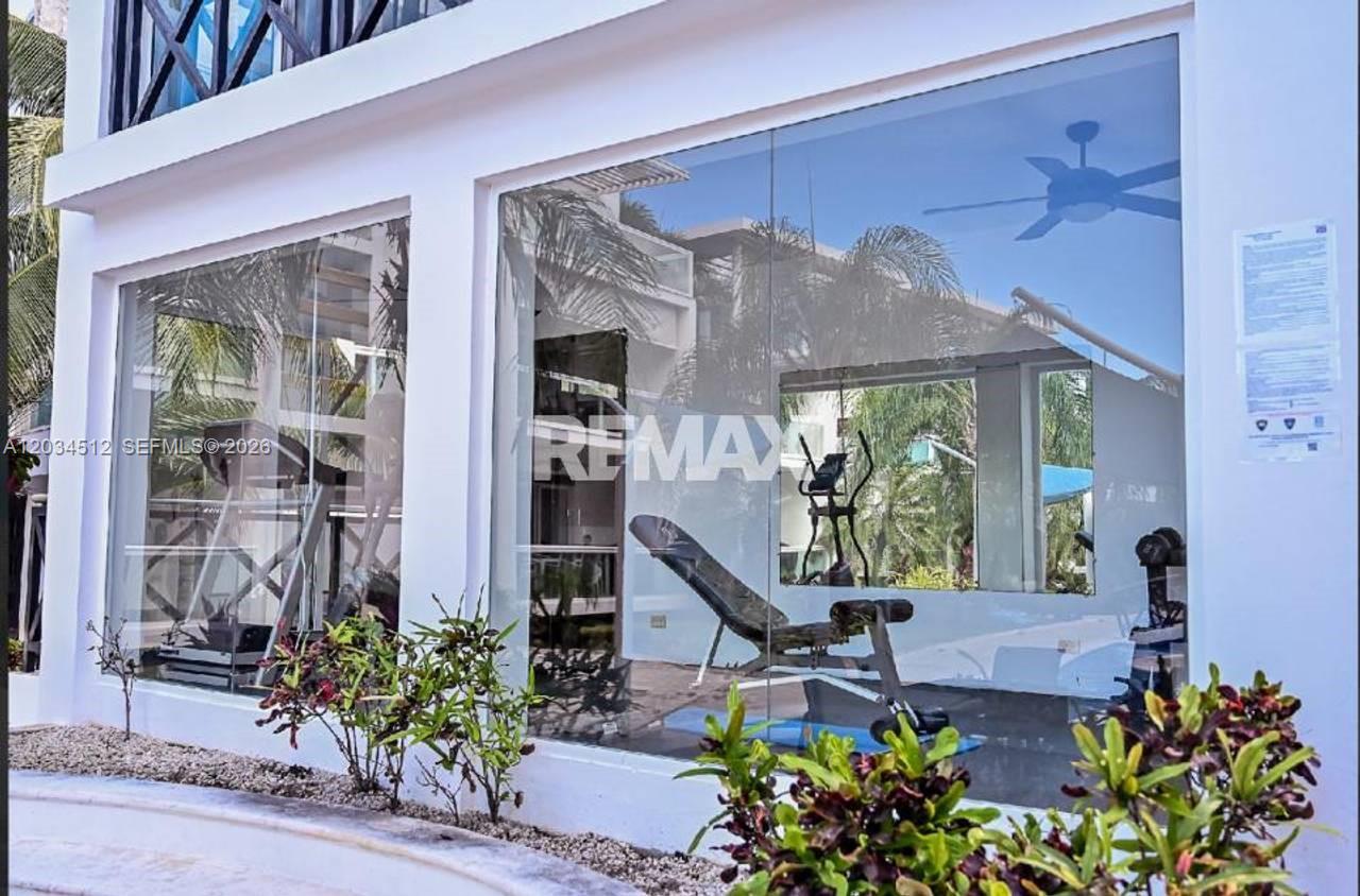 A ground-level view shows a fitness center with glass walls and exercise equipment inside — 1 El cortecito # 0, FL