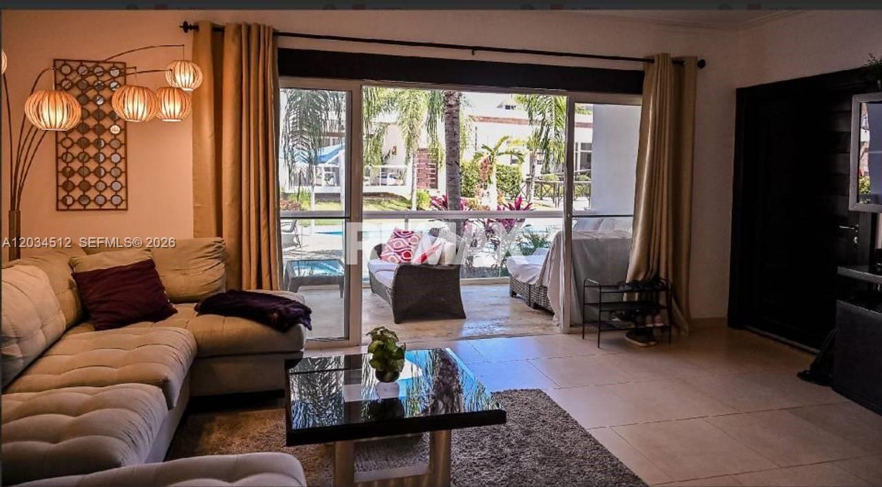 A living room features a sectional sofa, a glass coffee table, and sliding doors to a patio — 1 El cortecito # 0, FL