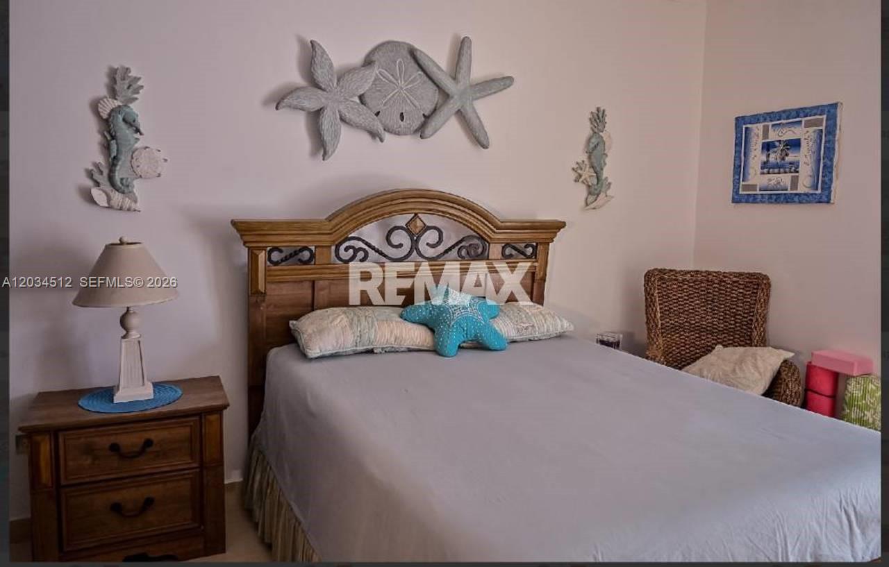 A bedroom features a wooden headboard, a gray bedspread, and coastal-themed wall decorations — 1 El cortecito # 0, FL