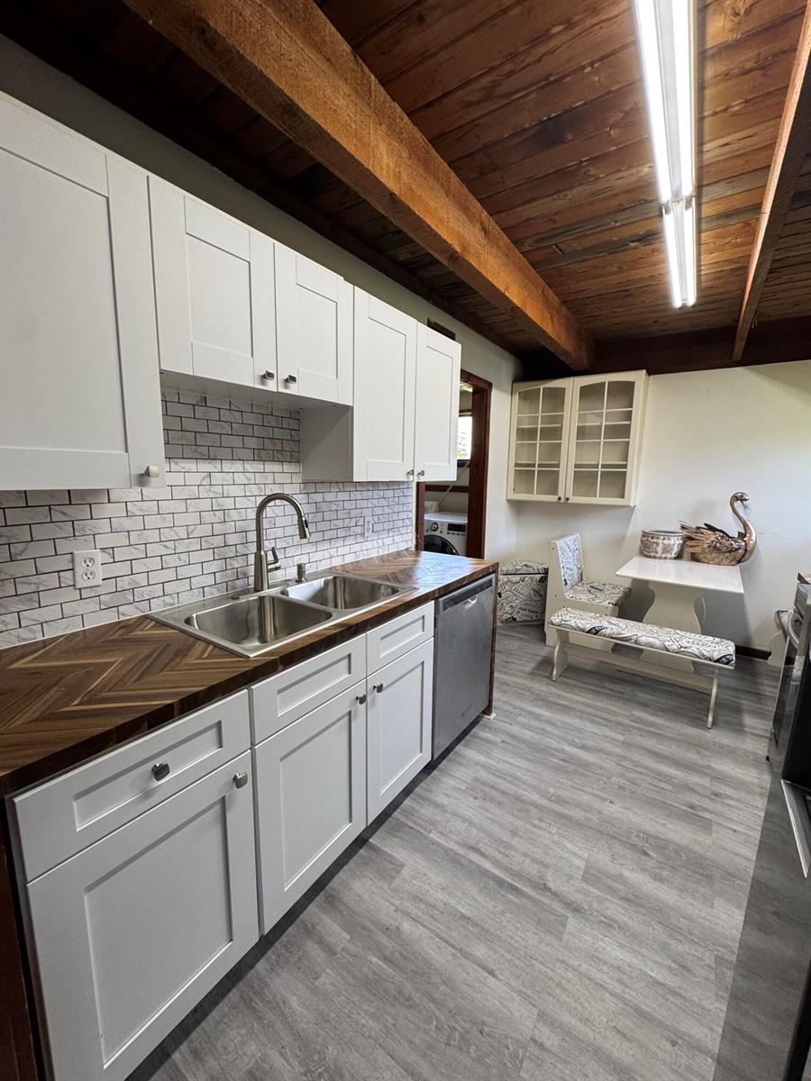 A kitchen features white cabinets, a herringbone wood countertop, and a subway tile backsplash — 5301 Sunset Boulevard, Fort Pierce FL 34982, FORT PIERCE, FL